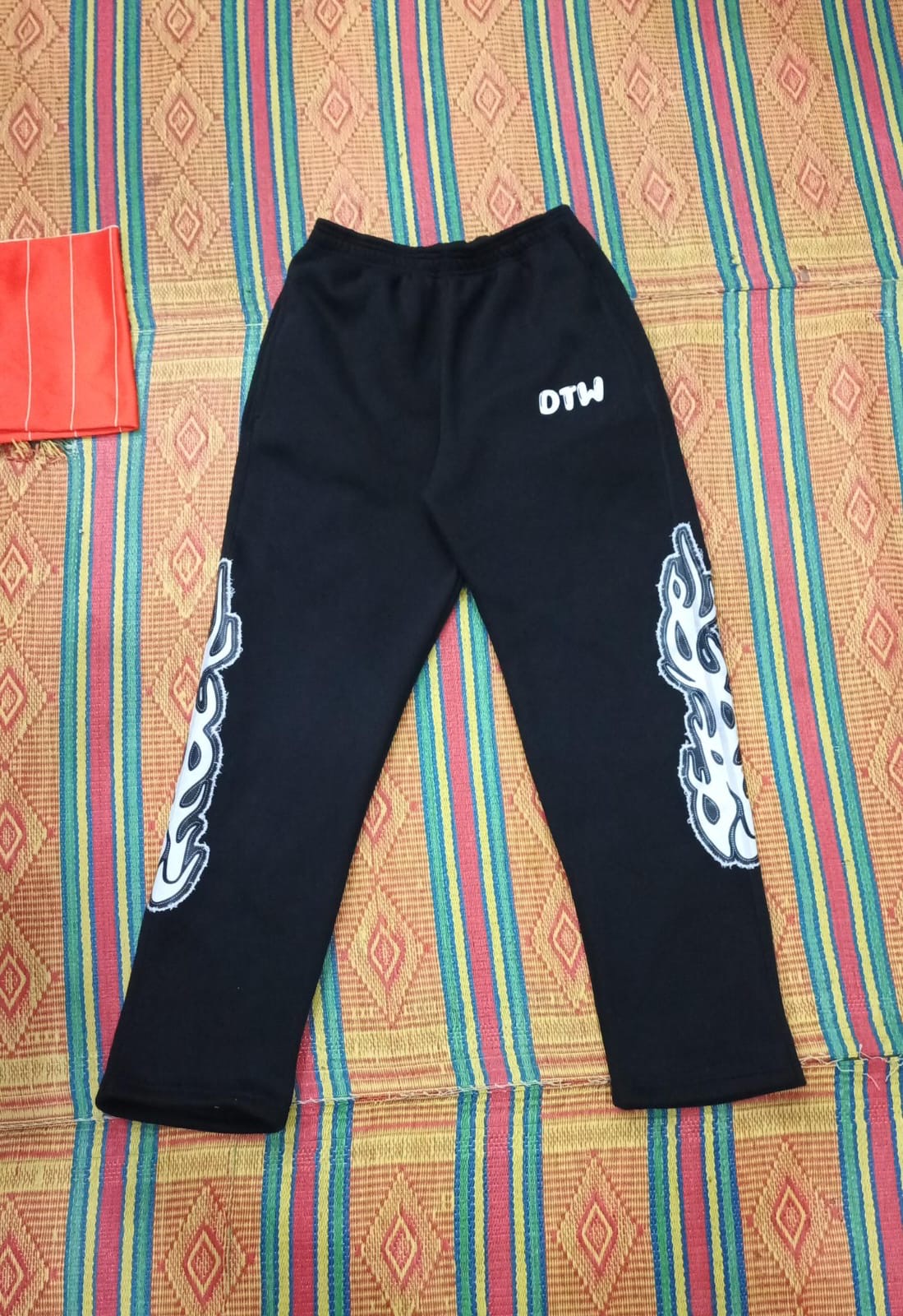 DTW Pants with bold flame-side detailing on a colorful patterned background.