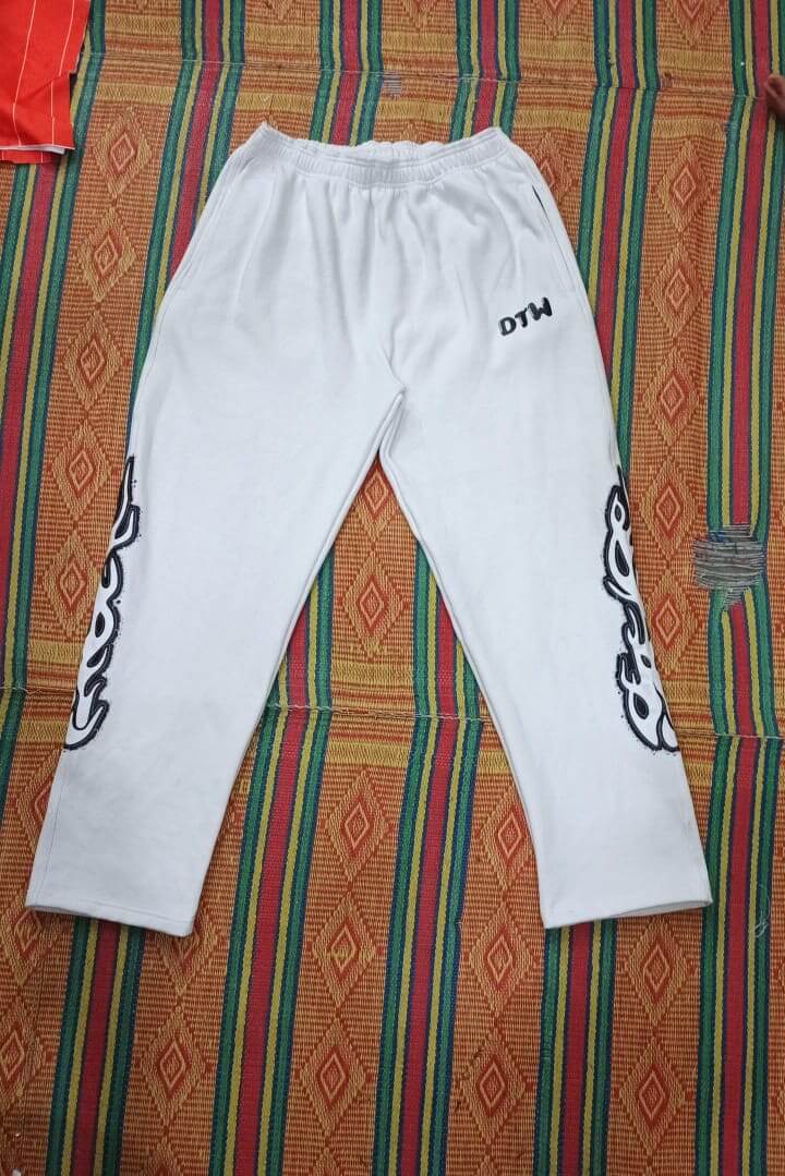 White DTW pants displayed on a colorful woven background, showcasing comfort and style for everyday wear.