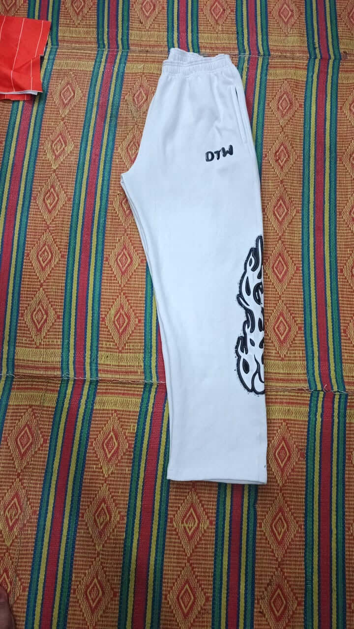 White DTW pants displayed on a patterned background showcasing their breathable and stylish design.
